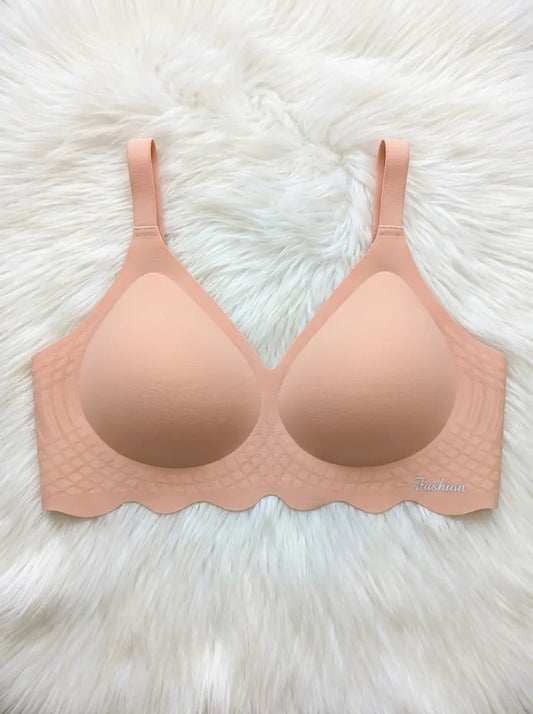 A peach-colored seamless wireless bra with scalloped edges and textured underband, laid flat on a white faux fur background.